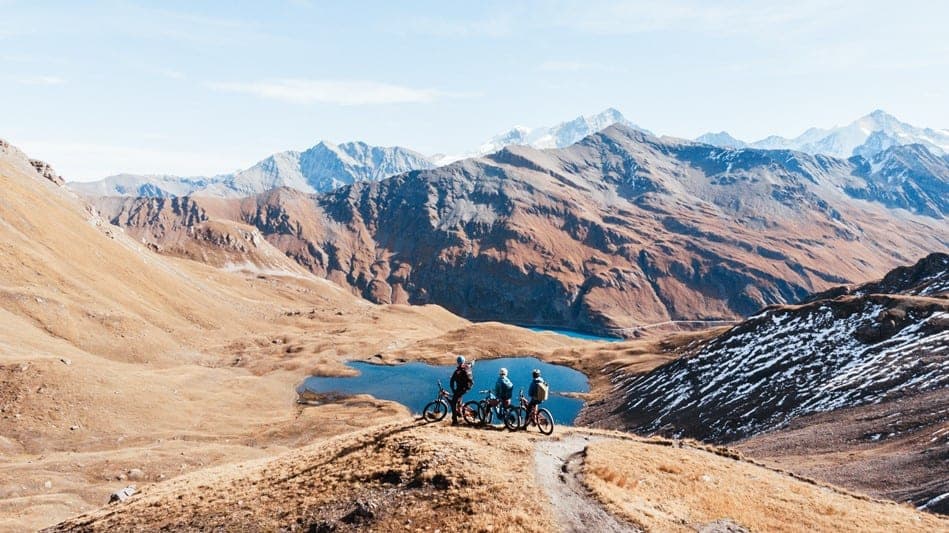 Riders taking the time to contemplate the majestic peaks and an Alpine Lake in Val d'Anniviers