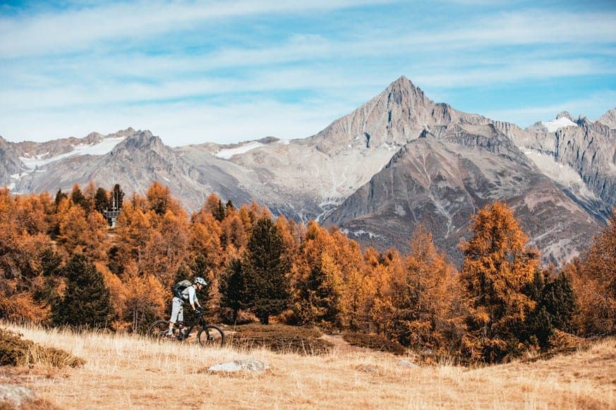 Female mountain biker riding with the Weisshorn in the backdrop