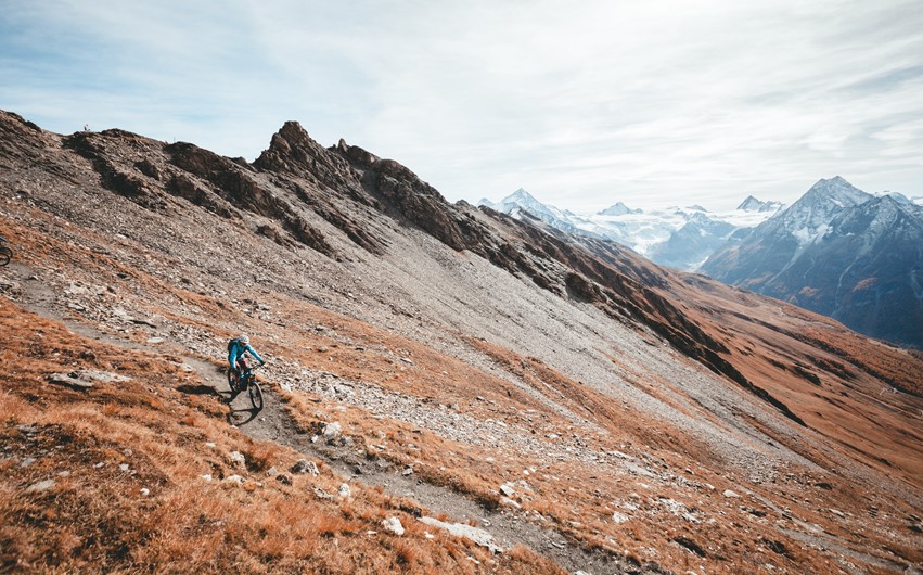 A rider enjoying a slice of Alpine singletrack with stunning views but some exposure, gradient and rocks